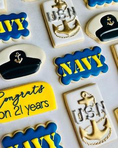 decorated cookies with navy insignias and names are displayed on a white tableclothed surface