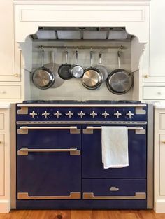 an old fashioned blue stove with pots and pans on it's hood in a kitchen