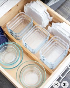 an open drawer with glass dishes in it