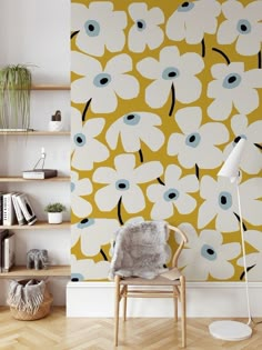 a chair sitting in front of a yellow wall with white and blue flowers on it