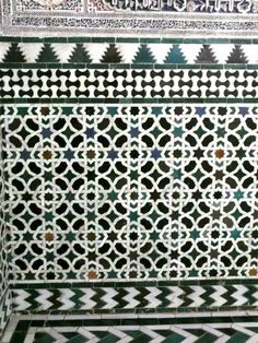 an intricately designed wall with green and white tiles