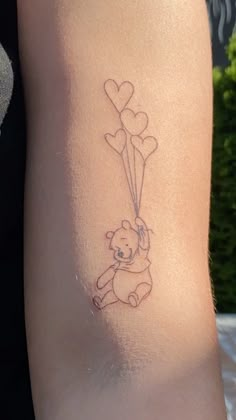 a small tattoo on the arm of a girl with a teddy bear holding a heart shaped balloon