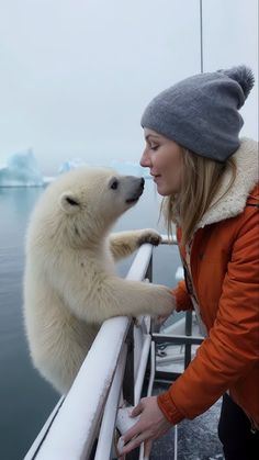 a woman petting a polar bear on top of a boat