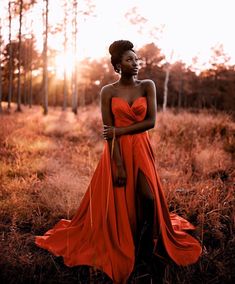 a woman in an orange dress is standing in the middle of a field with tall grass