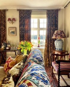 a living room filled with furniture next to a window covered in curtains and drapes