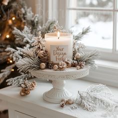 a white candle sitting on top of a cake plate next to a christmas tree and pine cones