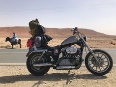 a motorcycle is parked on the side of the road with luggage strapped to it's back