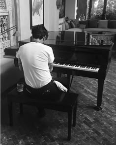 a man sitting on top of a piano in front of a black and white piano