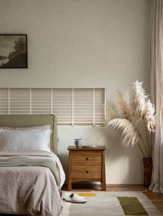 a bedroom with a bed, nightstand and rug on the floor in front of a window