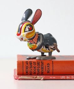 a small figurine is sitting on top of two books that are both red and black