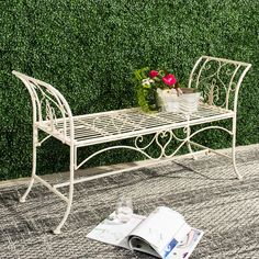 a table and chair sitting on the ground next to a bush with flowers in it