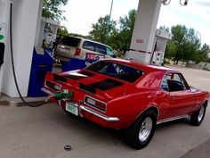 a red car is parked at a gas station