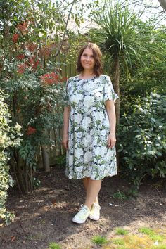 a woman standing in front of some bushes