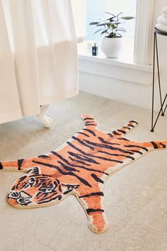 a tiger rug is laying on the floor in front of a window with a potted plant