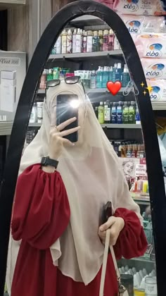 a woman taking a selfie with her cell phone in front of a store display