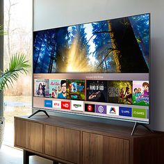 a flat screen tv sitting on top of a wooden cabinet in front of a window