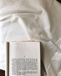 an open book sitting on top of a bed