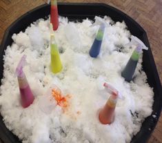 several different colored tubes in a black container filled with white powder and orange, pink, blue, yellow and green liquid