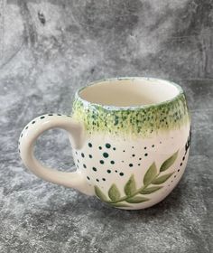 a green and white coffee cup sitting on top of a gray countertop next to a wall