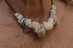 a close up of a person wearing a necklace with seashells hanging from it