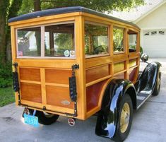 an old fashioned wooden car parked in front of a house