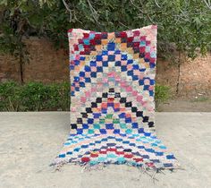 a multicolored rug sitting on top of a cement ground