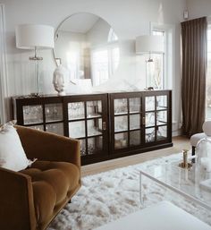 a living room filled with furniture and a large mirror on top of the wall above it