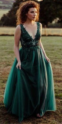 a woman standing in a field wearing a green dress