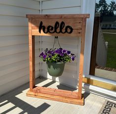 a potted plant sitting on top of a wooden frame with the word hello painted on it