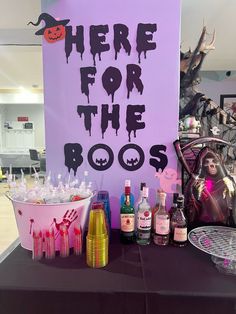 there is a purple sign that says here for the boos on it and some bottles