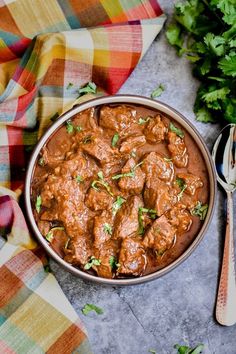 a bowl filled with meat and garnished with cilantro on a checkered table cloth