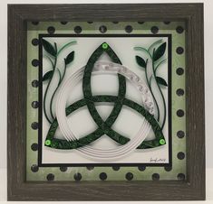 a decorative paper art piece with green leaves and circles in the shape of a celtic knot