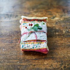 a small piece of fabric wrapped in twine and decorated with flowers on top of a wooden table