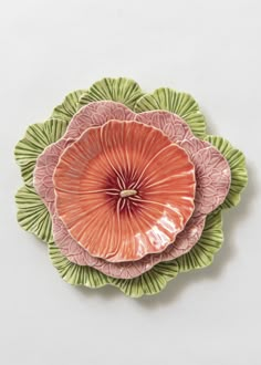 two pink and green plates sitting next to each other on top of a white surface