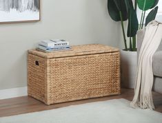 a wicker storage box with books on top in a living room area next to a couch