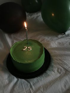 a green birthday cake with a lit candle