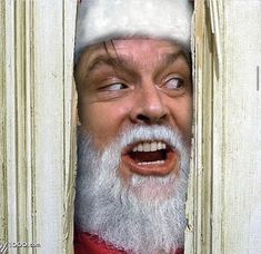 an old man wearing a santa claus hat looking through a hole in a door with his mouth open