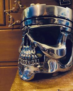 a metal skull head sitting on top of a wooden table