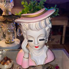 a white statue with a pink hat on it's head sitting next to other items