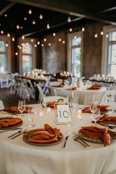 the table is set for an event with white linens and orange napkins