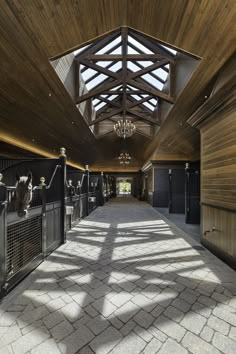 the inside of a horse stable with wooden walls and ceilings, along with stone flooring