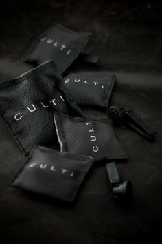 three zippered pouches with the words cut out on them sitting on a black surface