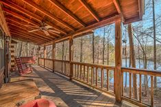 a covered porch with rocking chairs and a lake in the background