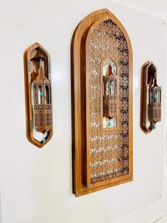 two wooden clocks mounted to the side of a white wall with intricate carvings on it