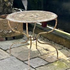 a small table sitting on top of a stone floor next to a potted plant