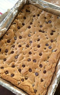 an uncooked chocolate chip cookie in a tin foil pan on a wooden table