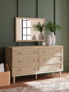 a large mirror sitting on top of a dresser next to a vase with a plant