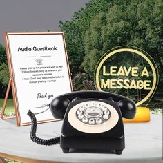 an old fashioned phone sitting on top of a table next to a sign that says leave a message