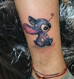 a small tattoo on the leg of a person with a pink and blue elephant design