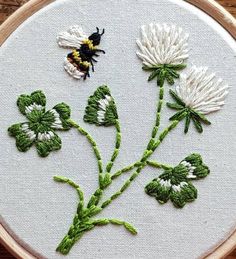 a close up of a embroidery on a wooden hoop with flowers and a bee in the middle